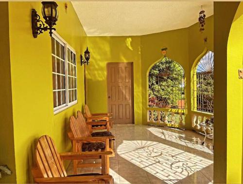 a yellow room with chairs and a door and windows at The Manor Deluxe Suite in Ocho Rios
