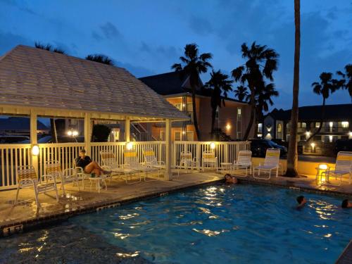 une personne assise sur des chaises dans une piscine la nuit dans l'établissement Seashell Village Resort near the beach with kitchens, à Port Aransas