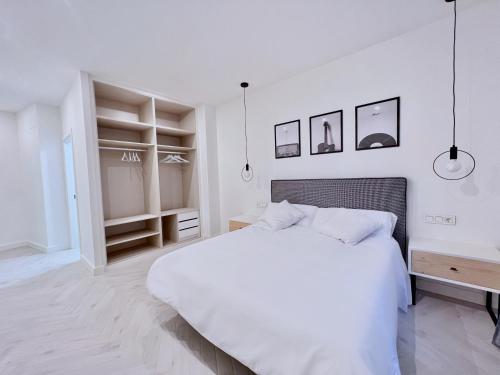 a white bedroom with a large white bed and shelves at Apartamento Domus in Teruel
