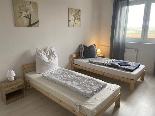 two beds in a room with a window at Wunderschöne neue Ferien und Monteurwohnung THM 17 in Wefensleben