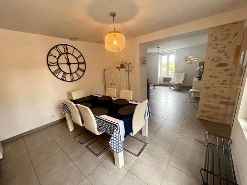 une salle à manger avec une table et une horloge au mur dans l'établissement Appartement 2 chambres lumineux, à Maisse