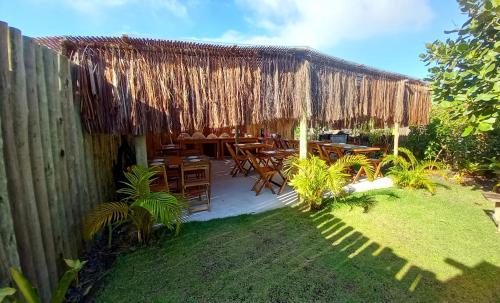 un patio con tavoli, sedie e tetto di paglia di Pousada Kiarô Caraíva a Caraíva