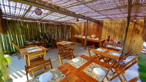 un restaurante con mesas de madera y sillas de madera en Pousada Kiarô Caraíva en Caraíva