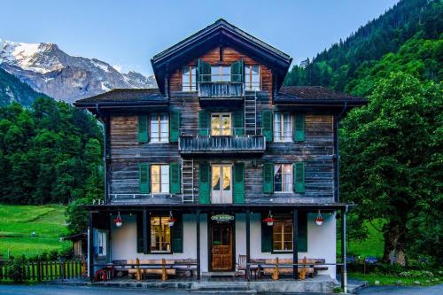 una gran casa de madera con bancos frente a ella en Alpenhof Mountain Lodge, en Stechelberg