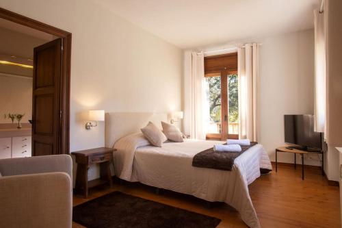 Habitación blanca con cama y TV en Casa con vistas al Parque Natural del Montseny, en Viladrau