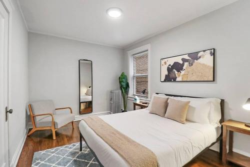 a white bedroom with a bed and a chair at Elegant & Stylishly 1BR Fully Furnished Apt - Lincoln 205 in Chicago