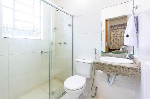 a bathroom with a shower and a toilet and a sink at Hotel Excelsior in Poços de Caldas