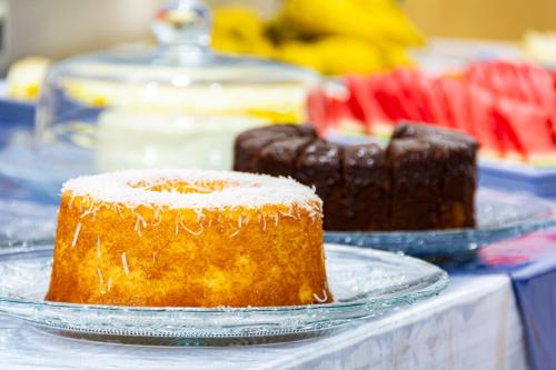 two cakes are sitting on plates on a table at Hotel Excelsior in Poços de Caldas