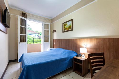 a bedroom with a blue bed and a window at Hotel Excelsior in Poços de Caldas