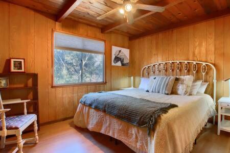 1 dormitorio con 1 cama, ventana y ventilador en Red Door Cottage Fireplace bbq 12 mi to Yosemite en Oakhurst