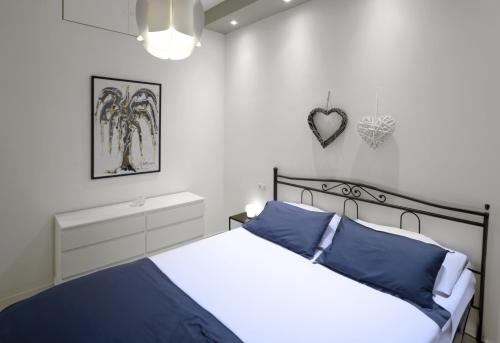 a white bedroom with a bed with blue pillows at Casa Fiorella in La Spezia