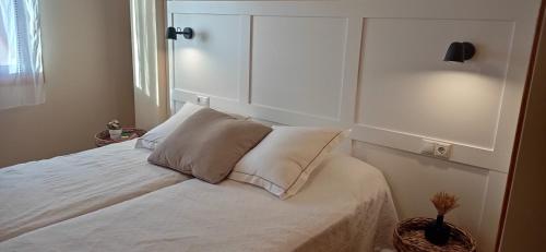 a bedroom with a white bed with a headboard at Lanzada Apartments in Sanxenxo