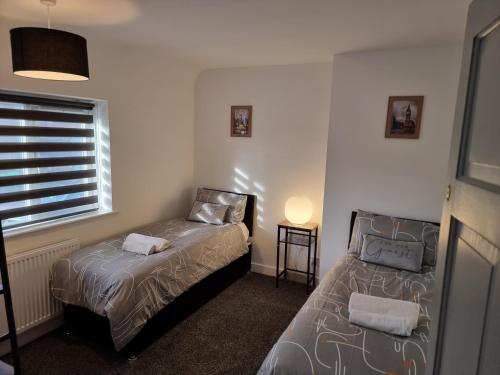 ノッティンガムにあるDulverton house - 3 bed house /sleeps 6+ driveway+close to M1のベッド2台と窓が備わる小さな客室です。
