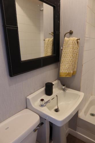 een badkamer met een witte wastafel en een spiegel bij An Cuilidh in Port Bannatyne