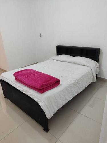Una cama con una almohada roja encima. en Departamento minimalista en Poza Rica de Hidalgo