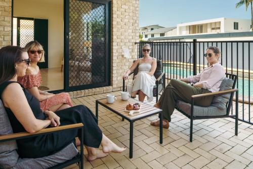 a group of people sitting in chairs on a patio at Sandy Feet Retreat in Warana in Buddina