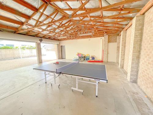 a ping pong table in a room with a brick wall at Sandy Feet Retreat in Warana in Buddina