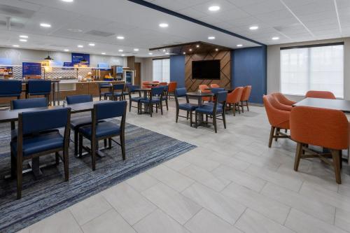 a dining room with tables and chairs and a tv at Holiday Inn Express Hotel & Suites Center Township, an IHG Hotel in Monaca