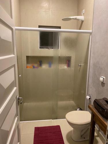 uma casa de banho com uma cabina de duche em vidro e um WC. em Casa Baronesa Suítes em São Sebastião