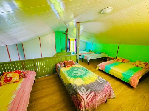 une chambre avec 3 lits dans une chambre verte dans l'établissement Teraupoo Lodge Chalet, à Afareaitu
