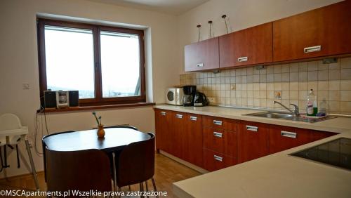 a kitchen with wooden cabinets and a table in it at MSC Apartments Zaciszny in Zakopane