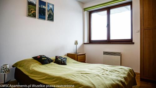 a bedroom with a bed with two pillows on it at MSC Apartments Zaciszny in Zakopane