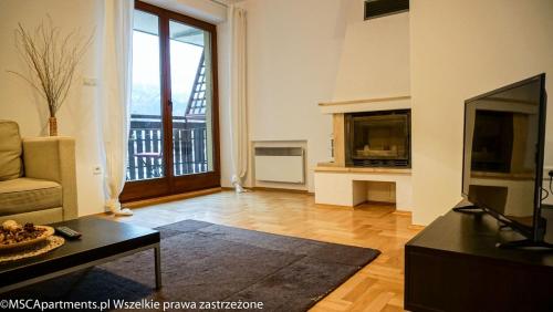 ザコパネにあるMSC Apartments Zacisznyのリビングルーム(テレビ、ソファ、テーブル付)