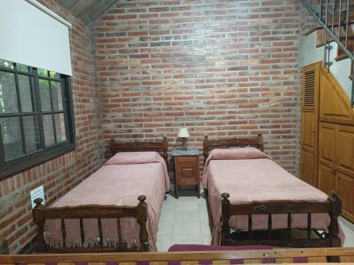 2 camas en una habitación con una pared de ladrillo en Departamento Loft en Embalse