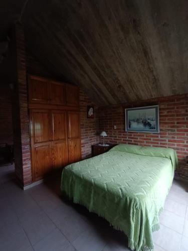 Un dormitorio con una cama verde y una pared de ladrillo en Departamento Loft en Embalse