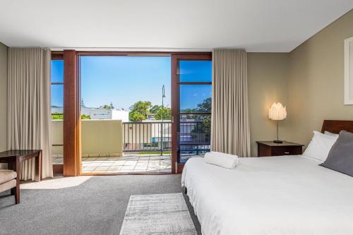 Habitación de hotel con cama y balcón en Byron Bay Accom Unit 6 21-25 Fletcher Street - A Seventh Heaven, en Byron Bay