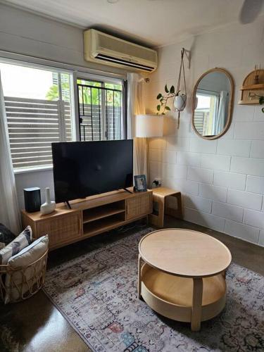 a living room with a flat screen tv and a table at Prime location: Just steps away from Oxford Street in Brisbane