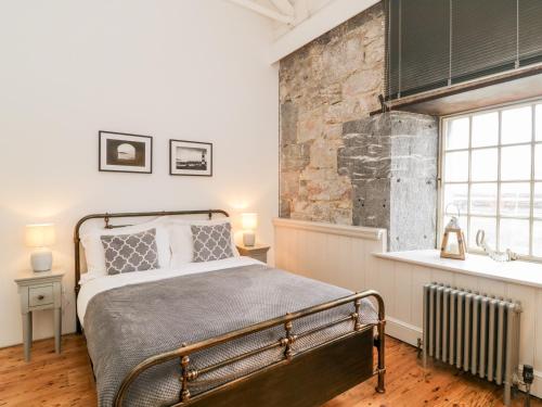 um quarto com uma cama e uma parede de tijolos em Clarence Riverside, Royal William Yard em Plymouth