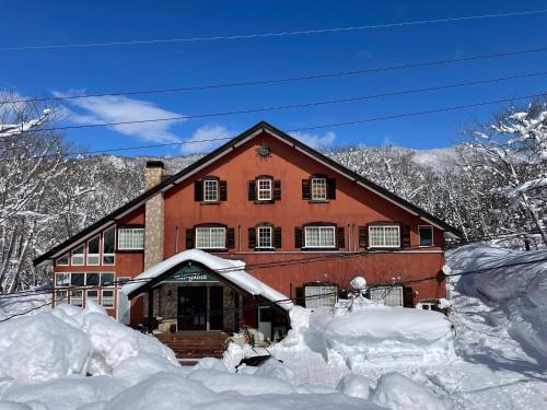 a house covered in snow with a pile of snow at マウンテンリゾート・マルガンタ Marganta in Madarao Kogen