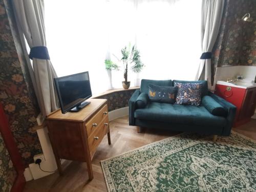 a living room with a couch and a television at Woodside House in Bexhill