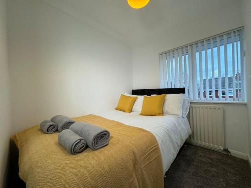 1 dormitorio con 2 camas con almohadas amarillas y ventana en Cosy 3BR Modern Home Middlesbrough, en Middlesbrough