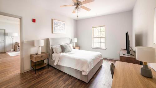- une chambre blanche avec un lit et un ventilateur de plafond dans l'établissement Landing Modern Apartment with Amazing Amenities (ID8014X44), à Covington