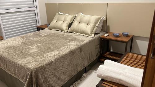 a bedroom with a bed with pillows and two tables at Apartamento Luxo em Uberaba in Uberaba