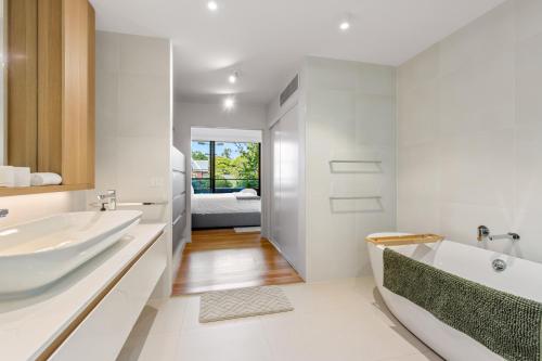 a white bathroom with a tub and a sink at Fantastic 3-Bed Home by Melbourne Uni & Zoo in Melbourne