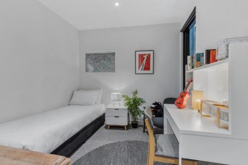 een witte slaapkamer met een bed en een bureau bij Lovely & Quiet 2-Bed in the Heart of Carlton in Melbourne