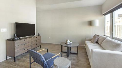 ein Wohnzimmer mit einem Sofa, einem Tisch und einem TV in der Unterkunft Landing Modern Apartment with Amazing Amenities (ID1220X094) in Omaha