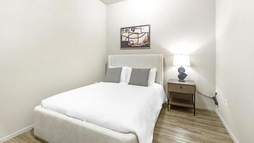 ein weißes Schlafzimmer mit einem weißen Bett und einem Tisch in der Unterkunft Landing Modern Apartment with Amazing Amenities (ID1220X094) in Omaha