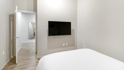 ein weißes Schlafzimmer mit einem Bett und einem Flachbild-TV in der Unterkunft Landing Modern Apartment with Amazing Amenities (ID1220X094) in Omaha