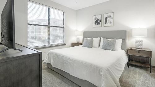 - une chambre blanche avec un lit et une télévision à écran plat dans l'établissement Landing Modern Apartment with Amazing Amenities (ID1191X124), à San Antonio