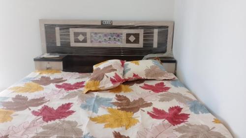 - un lit avec une couette à motifs de feuilles et 2 oreillers dans l'établissement Hotel Kota kitchen INN and restaurant., à Kota