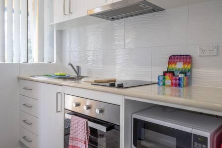 una cocina con encimera y microondas en Seafront Getaway Studio, Great Location with Pool, en Batehaven