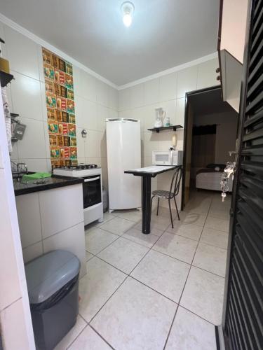 a small kitchen with a table and a refrigerator at Kit Net Vitoria 01 in Bauru