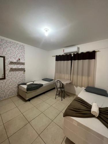 1 dormitorio con 2 camas y mesa. en Kit Net Vitoria 01, en Bauru