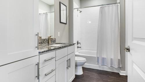 a white bathroom with a toilet and a bath tub at Landing Modern Apartment with Amazing Amenities (ID1286X424) in Chapel Hill