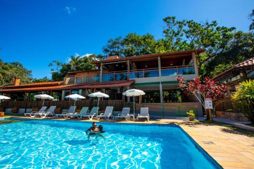 a person in a swimming pool with a house in the background at Pousada Iguatiba in Paraibuna