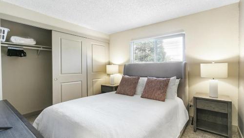 um quarto com uma cama branca, 2 candeeiros e uma janela em Landing Modern Apartment with Amazing Amenities (ID8880X29) em Federal Way